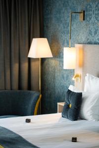 a hotel room with a bed with a lamp and a chair at James Boutique Hôtel Colmar centre in Colmar