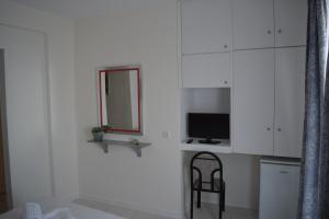 a white kitchen with a chair and a television at Kangaroo Hotel in Mola Kalyva