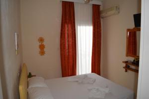 a bedroom with a white bed in front of a window at Kangaroo Hotel in Mola Kalyva