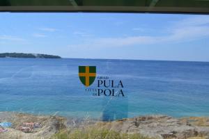 a view of the ocean from a window with the words pula oh pula at Apartments Nicole in Pula