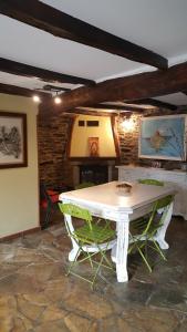 a white table and two green chairs in a room at Pensión Albergue A Pedra in Sarria