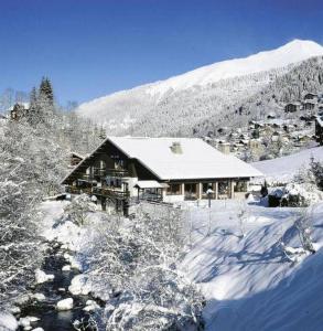 dom pokryty śniegiem przed górą w obiekcie Hotel Le Soly w mieście Morzine