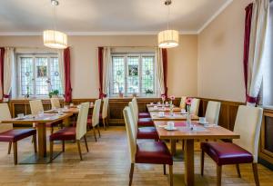 a restaurant with wooden tables and chairs and windows at Laimer Hof am Schloss Nymphenburg in Munich
