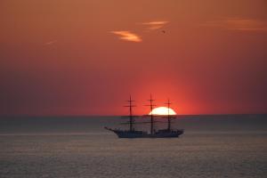 a ship in the ocean with a sunset in the background at Aquarius Hotel in Scheveningen