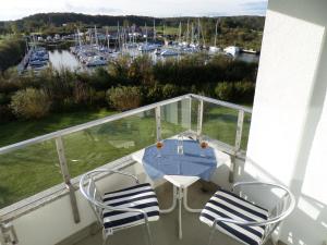 einen Balkon mit einem Tisch und Stühlen sowie einen Yachthafen in der Unterkunft Meeresbrise Schausende in Glücksburg