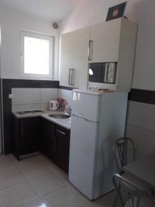 a small kitchen with a white refrigerator and a microwave at Apartments Pehar in Zaostrog