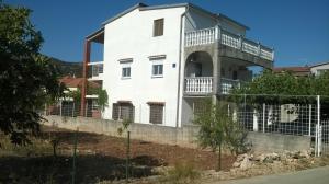 a white building with a balcony on top of it at Apartmani Parlov in Vinišće