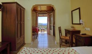 a bedroom with a bed and a desk and a balcony at Pansion Nikos in Patitiri