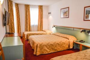 Habitación de hotel con 2 camas y TV en Hotel Sport, en Ledro