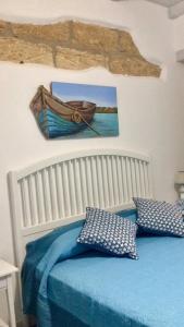 Ca&Sa Sweet Holiday في شينيسي: سرير ملايات زرقاء وصورة قارب على الحائط
