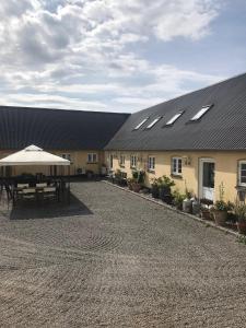 un edificio con una mesa y una sombrilla delante de él en Strandsegård Ferielejlighed, en Ølsted