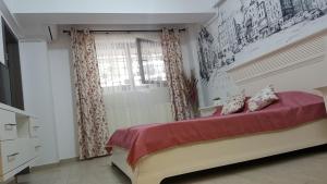 Schlafzimmer mit einem Bett mit roter Bettwäsche und einem Fenster in der Unterkunft Tina Apartament 2 in Craiova
