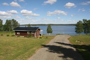 une maison sur le côté d'une route à côté d'un lac dans l'établissement Harjuniemi, à Kangosjärvi