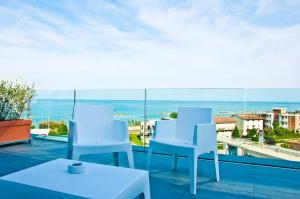 Un balcón con sillas blancas y vistas al océano. en Ambruosi Village Resort & SPA, en Massignano