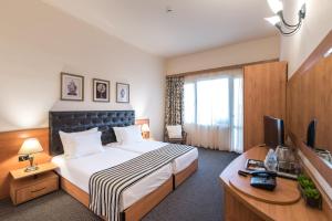 a hotel room with a bed and a desk and a television at Lotus Family Hotel - Free Parking in Sunny Beach