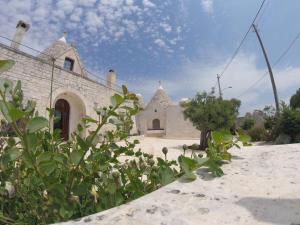 un edificio in pietra con un cortile con piante di fronte di B&B Via dei Trulli a Cisternino Altre 36 foto