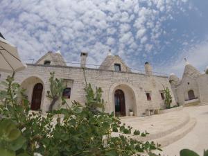 un grande edificio in pietra con un cielo azzurro con nuvole di B&B Via dei Trulli a Cisternino