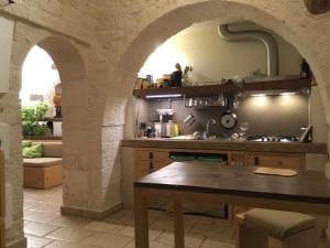 una cocina con un arco de piedra y una mesa en B&B Via dei Trulli, en Cisternino