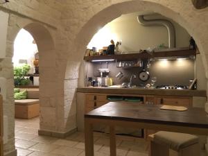 una cucina con arco in pietra e tavolo di B&B Via dei Trulli a Cisternino