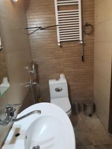 uma casa de banho com um lavatório branco e um WC. em Apartment Irma Rustaveli 57 em Batumi