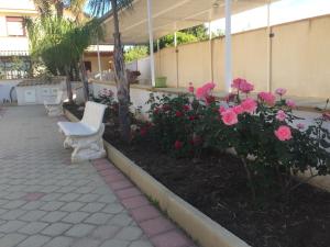 a patio with two white chairs and pink flowers at Villa Marta in San Leone