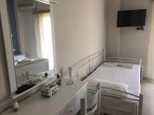 a white bedroom with a bed and a mirror at Spyridonou House in Parga