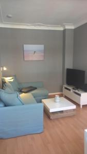 ein Wohnzimmer mit einem blauen Sofa und einem Fernseher in der Unterkunft Quartier im Burghof in Flensburg