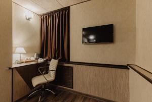 um quarto de hotel com uma cadeira, uma secretária e uma televisão em Helix Hotel em Sochi