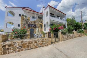 a house with a stone wall and a fence at Irida Holiday Apartments in Stoupa