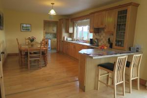a kitchen with wooden cabinets and a table with chairs at THISTLEDOWN - Ballina - Crossmolina - County Mayo - Sleeps 8 - Sister property to Inglewood in Ballina