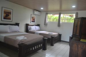 a bedroom with two beds and a window at Hotel Don Fito in Golfito