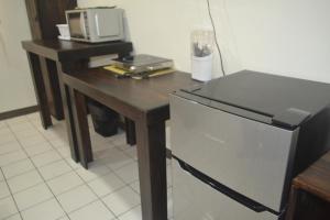 eine Küche mit einem Tisch, einer Mikrowelle und einem Kühlschrank in der Unterkunft Hotel Don Fito in Golfito