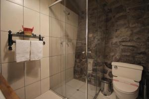 y baño con ducha de cristal y aseo. en LLipimpac House, en Cusco