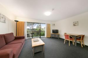 uma sala de estar com um sofá e uma mesa em Mt Ommaney Hotel Apartments em Brisbane