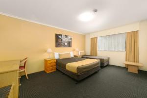 a hotel room with a bed, chair, and nightstand at Mt Ommaney Hotel Apartments in Brisbane