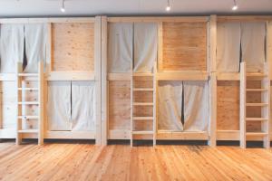 a room filled with wooden bunk beds with windows at Noboribetsu Guest House AKA & AO in Noboribetsu