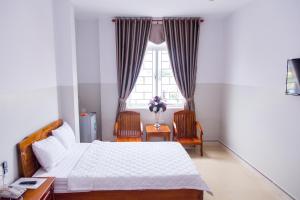 a bedroom with a bed and a table and a window at Hoang Thinh Hotel in Kon Tum