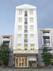a tall white building with a man standing in front of it at Hoang Thinh Hotel in Kon Tum (2)