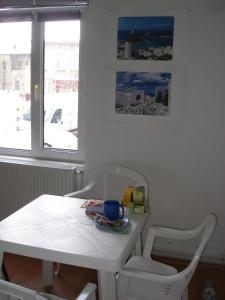 una mesa y sillas blancas en una habitación con ventana en Kretan Hostel, en Bucarest