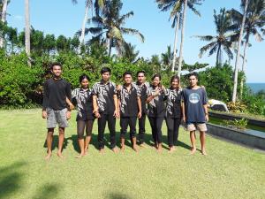 a group of young men posing for a picture on the grass at Villa Rumah Pantai Bali in Selemadeg