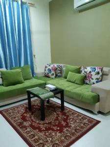 uma sala de estar com um sofá verde e uma mesa de centro em Jawharet Al Kheir Furnished Apartments em Salalah