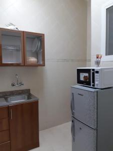 a kitchen with a microwave on top of a refrigerator at Jawharet Al Kheir Furnished Apartments in Salalah
