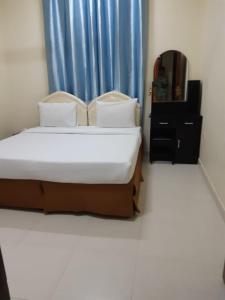 um quarto com uma cama e uma cortina azul em Jawharet Al Kheir Furnished Apartments em Salalah