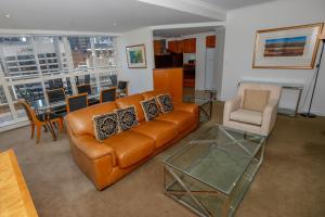 a living room with a leather couch and a glass table at Bond 1603 Self Catering in Sydney