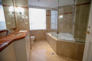 a bathroom with a tub and a toilet and a sink at Bond 1603 Self Catering in Sydney +5 photos