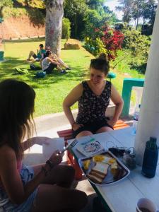 a woman sitting on a table with a plate of cake at Ella Escapade Hostel by Nomadic in Ella