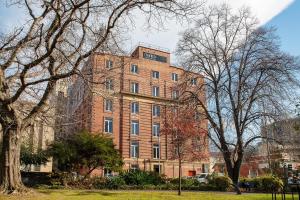 a red brick building with trees in front of it at Mantra One Sandy Bay Road in Hobart