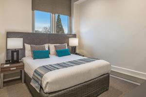 a bedroom with a large bed and a large window at Mantra One Sandy Bay Road in Hobart