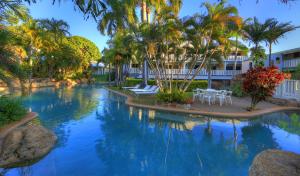 una piscina con palmeras y sillas en un complejo en Sovereign Resort Hotel, en Cooktown