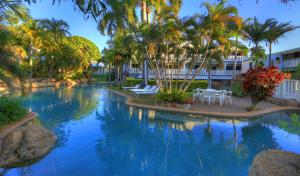 - une piscine entourée de palmiers et de chaises dans un complexe dans l'établissement Sovereign Resort Hotel, à Cooktown